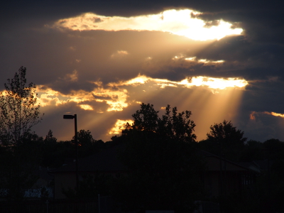 [Zoomed in on the prior photo to show the openings in the clouds with the sun rays beaming down on the houses and trees.]